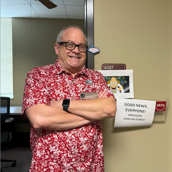 Rick Dowling standing with arms crossed next to a sign that says "Good news, everyone"